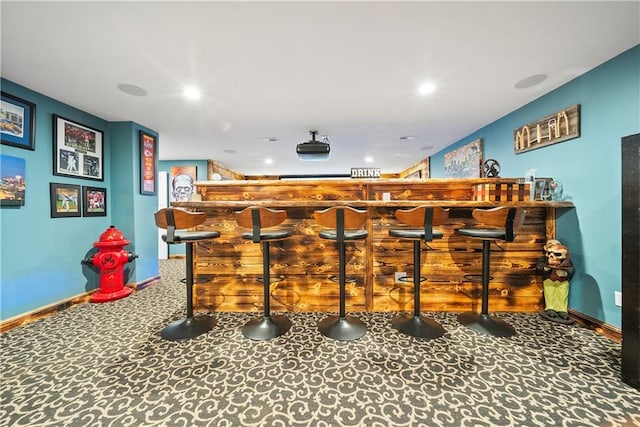 bar featuring baseboards, recessed lighting, a bar, and carpet