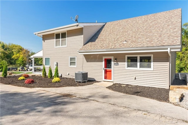 view of front of home with central AC unit and a shingled roof