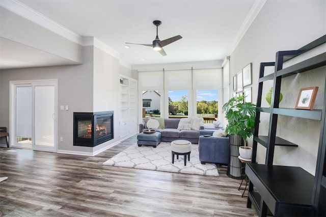 living room featuring a multi sided fireplace, crown molding, hardwood / wood-style floors, and ceiling fan