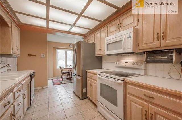 kitchen featuring sink, backsplash, light brown cabinetry, light tile patterned flooring, and appliances with stainless steel finishes