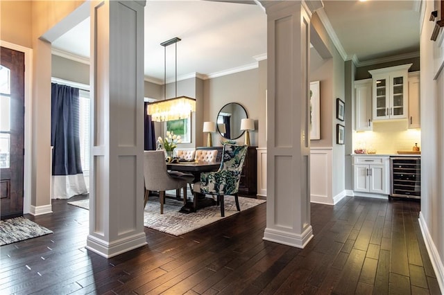 16924 Futura St, Overland Park, KS 66085 - foyer entrance featuring beverage cooler, decorative columns, dark wood finished floors, crown molding, and bar area