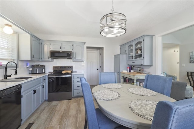 kitchen featuring stainless steel appliances, sink, decorative light fixtures, an inviting chandelier, and light hardwood / wood-style flooring