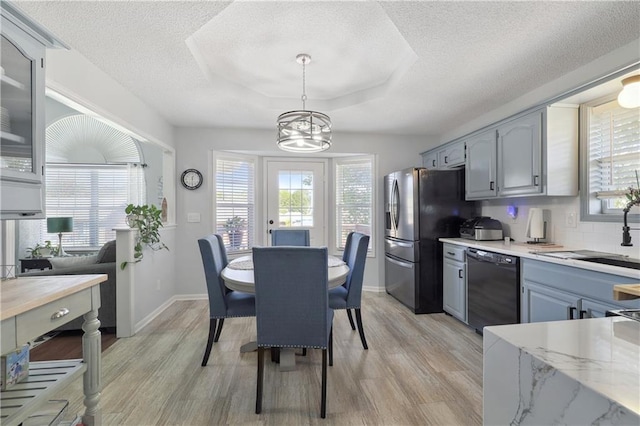 kitchen with light hardwood / wood-style floors, sink, black dishwasher, gray cabinets, and hanging light fixtures