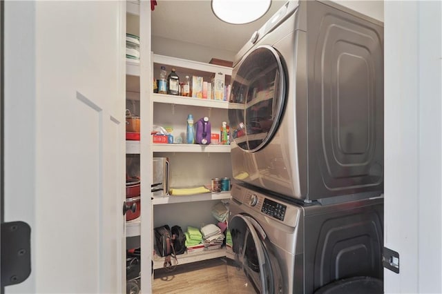 laundry area with hardwood / wood-style flooring and stacked washer and clothes dryer