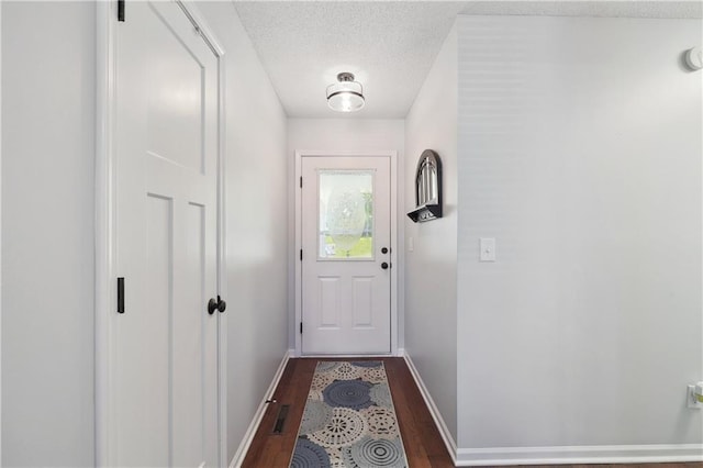 doorway to outside featuring a textured ceiling and dark hardwood / wood-style flooring