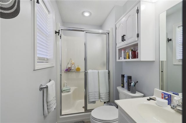 bathroom featuring vanity, toilet, a shower with door, and a textured ceiling