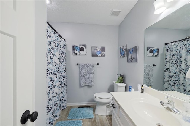 bathroom featuring vanity, toilet, wood-type flooring, and a textured ceiling