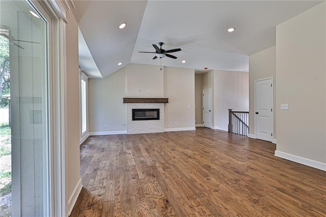 unfurnished living room featuring a brick fireplace, lofted ceiling, dark wood-type flooring, and ceiling fan