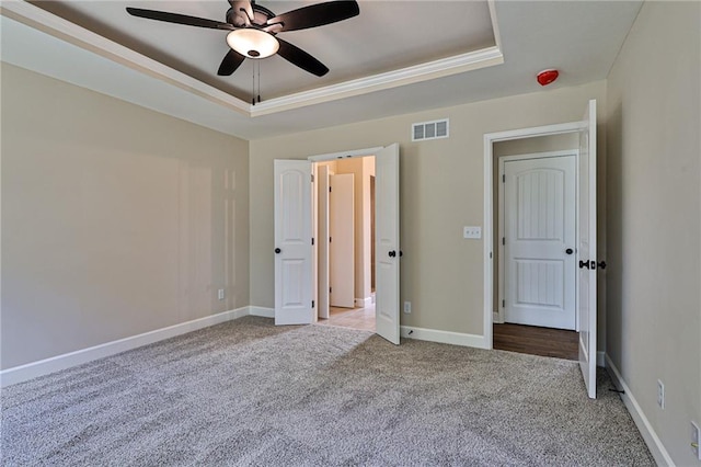 unfurnished bedroom with carpet flooring, a tray ceiling, and ceiling fan