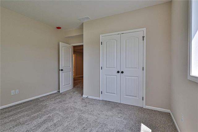 unfurnished bedroom featuring light colored carpet and a closet