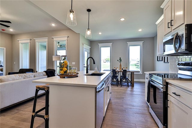 kitchen featuring white cabinets, an island with sink, sink, appliances with stainless steel finishes, and dark hardwood / wood-style floors