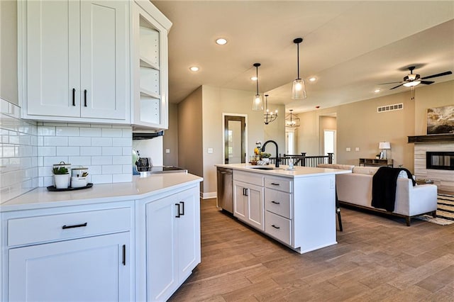 kitchen featuring white cabinets, pendant lighting, stainless steel appliances, light hardwood / wood-style flooring, and a kitchen island with sink