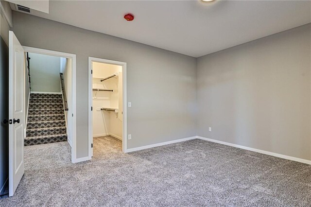 unfurnished bedroom featuring light colored carpet, a closet, and a walk in closet