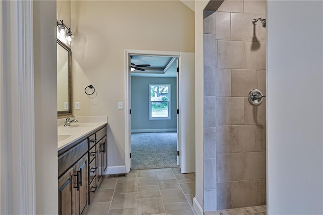 bathroom featuring a tile shower, tile patterned flooring, vanity, and ceiling fan