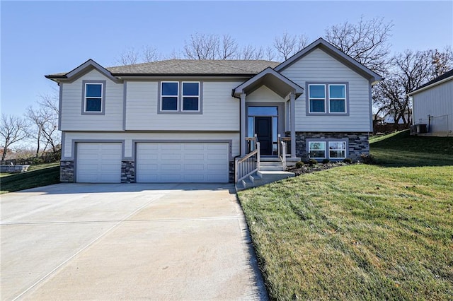 bi-level home featuring a front yard, an attached garage, and stone siding