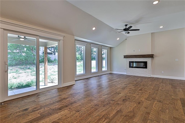 unfurnished living room with dark wood-style flooring, a glass covered fireplace, lofted ceiling, and ceiling fan