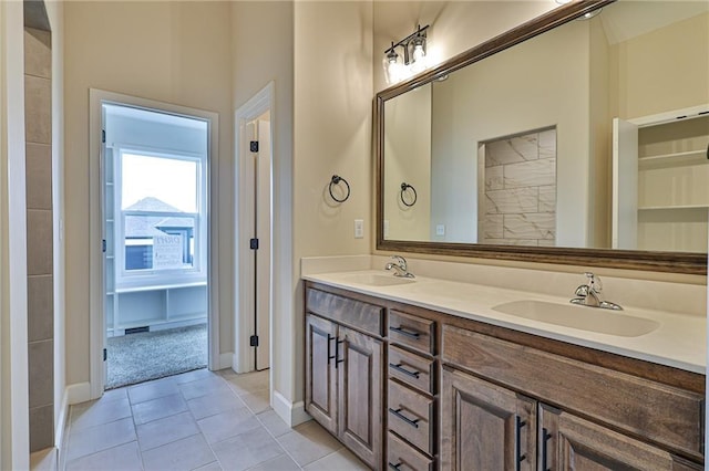 bathroom with baseboards, double vanity, a sink, and tile patterned flooring