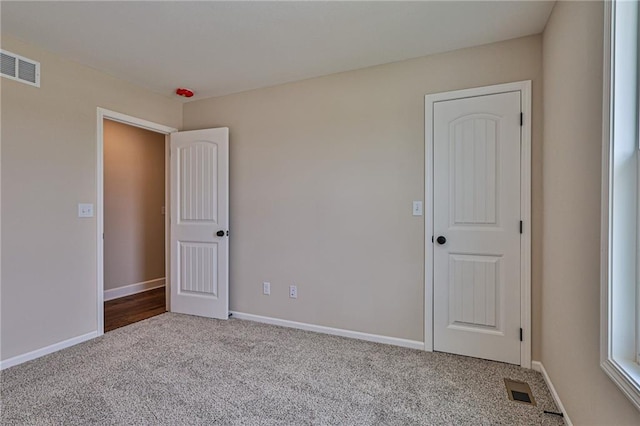 unfurnished room with baseboards, carpet floors, and visible vents