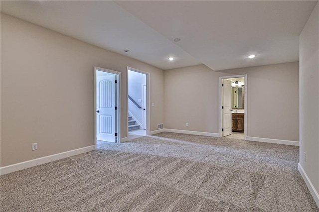 empty room with light colored carpet, recessed lighting, stairs, and baseboards