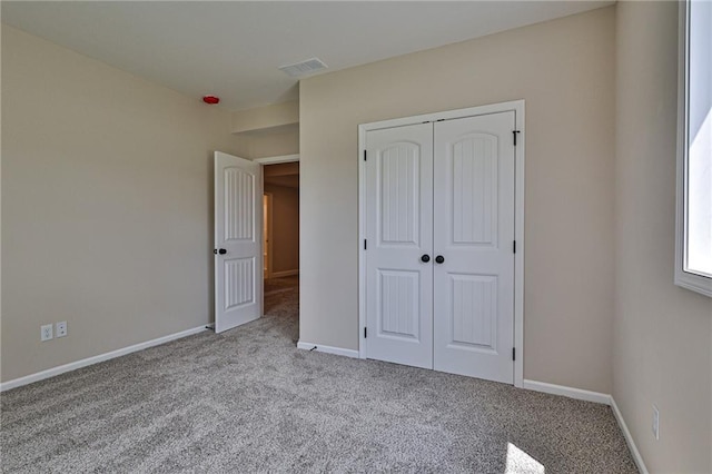 unfurnished bedroom featuring carpet flooring, a closet, baseboards, and visible vents