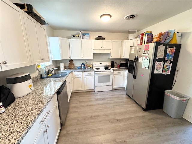 kitchen with white cabinets, sink, appliances with stainless steel finishes, light stone countertops, and light hardwood / wood-style floors