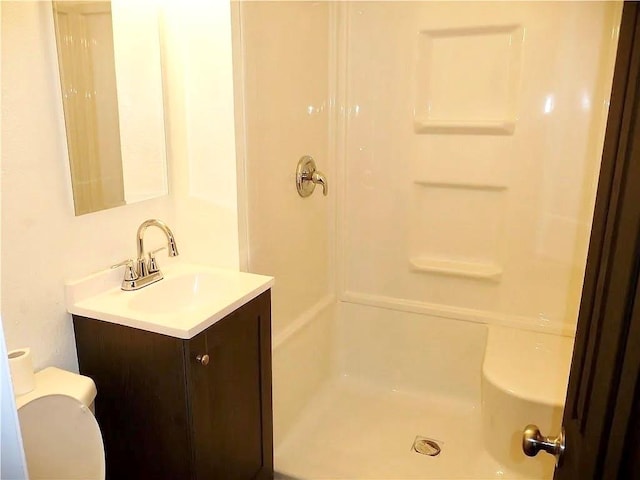 bathroom featuring a shower, vanity, and toilet