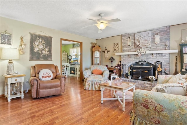 living room featuring a brick fireplace, ceiling fan, and wood-type flooring