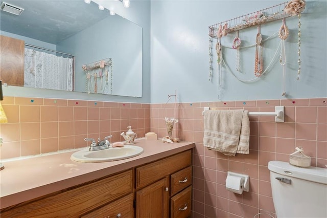 bathroom with vanity, tile walls, and toilet