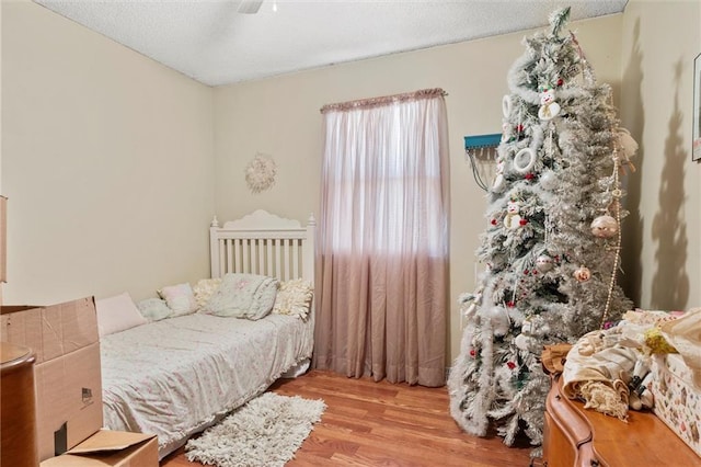 bedroom featuring light hardwood / wood-style flooring, a textured ceiling, and ceiling fan