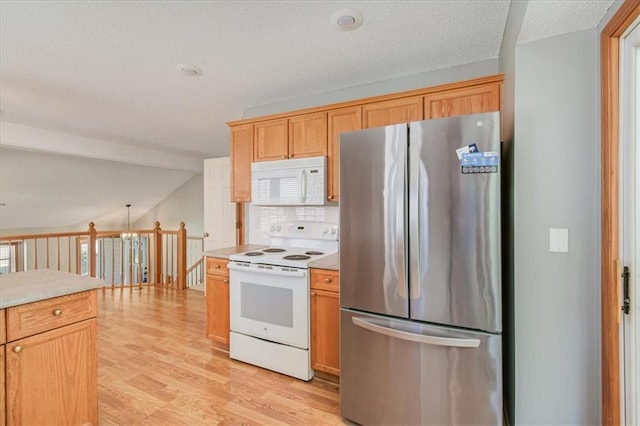 kitchen featuring tasteful backsplash, white appliances, light hardwood / wood-style floors, and a textured ceiling