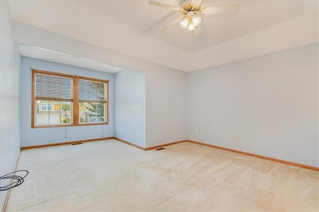 carpeted empty room with ceiling fan and a raised ceiling