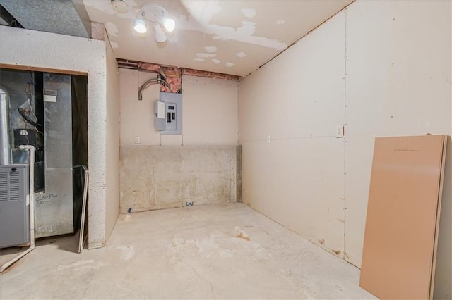 basement with electric panel, white refrigerator, and heating unit