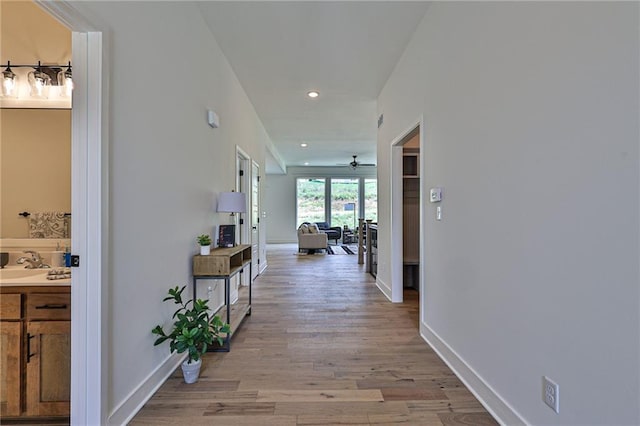 hallway with light hardwood / wood-style flooring and sink