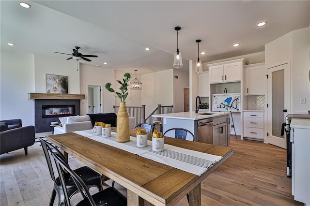 dining room featuring ceiling fan with notable chandelier, light hardwood / wood-style flooring, and sink