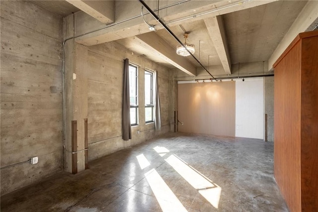 spare room with beam ceiling and concrete floors