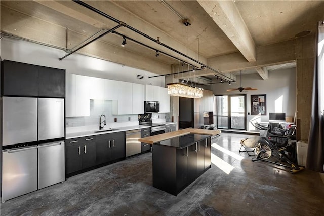 kitchen with sink, decorative light fixtures, white cabinetry, stainless steel appliances, and a center island