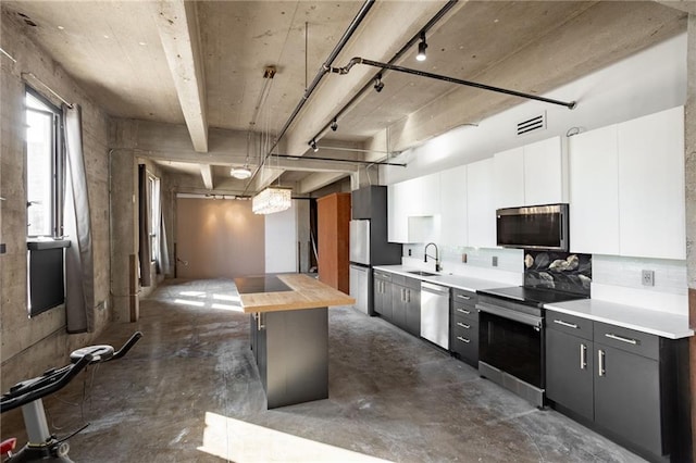 kitchen featuring decorative light fixtures, sink, butcher block counters, appliances with stainless steel finishes, and white cabinetry