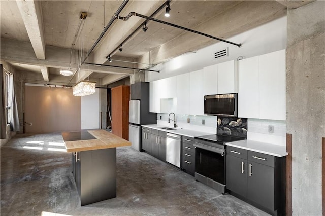 kitchen with decorative light fixtures, sink, wood counters, appliances with stainless steel finishes, and white cabinetry