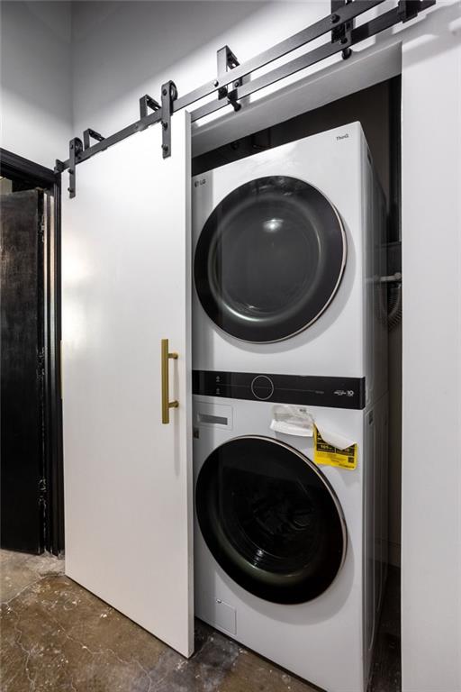 laundry room featuring a barn door and stacked washer / drying machine