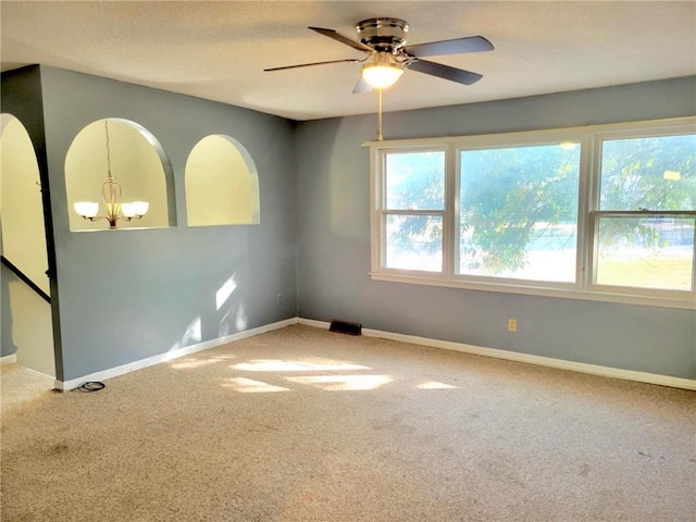 carpeted empty room with ceiling fan with notable chandelier