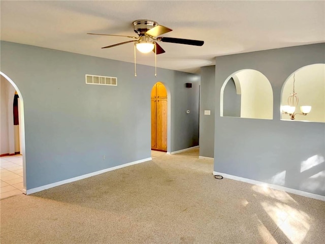 carpeted spare room with ceiling fan with notable chandelier