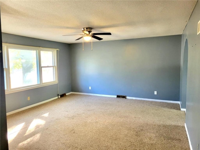 carpeted spare room with a textured ceiling and ceiling fan