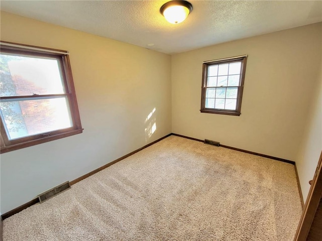 carpeted empty room featuring a textured ceiling