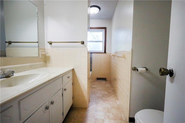 bathroom featuring vanity, toilet, and tile walls