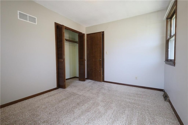 unfurnished bedroom with light carpet and a closet