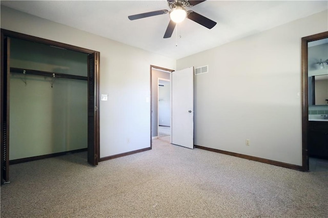 unfurnished bedroom featuring light carpet, a closet, ensuite bathroom, and ceiling fan