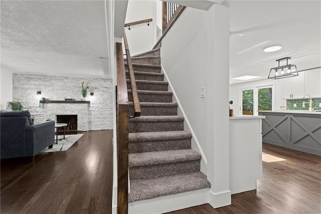 staircase featuring wood-type flooring, a fireplace, and sink