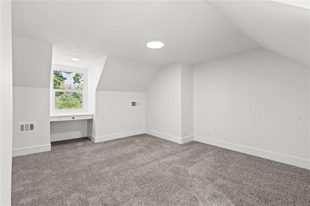 additional living space with lofted ceiling, carpet flooring, and built in desk