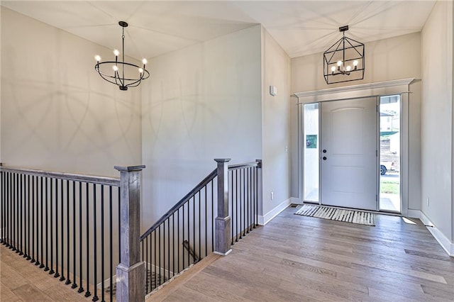 entryway with an inviting chandelier, baseboards, and wood finished floors