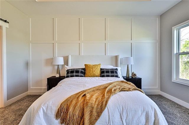 bedroom featuring multiple windows, dark carpet, and a decorative wall
